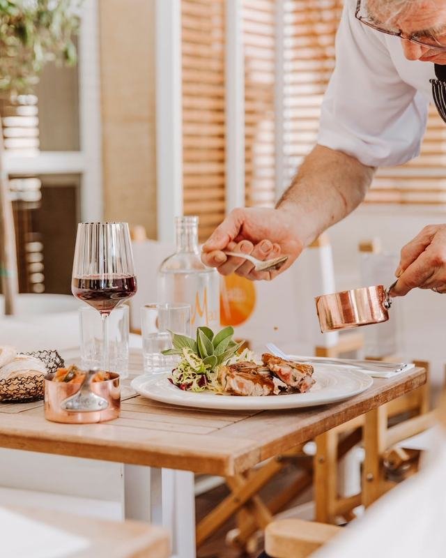 Assiette d'agneau dressée en salle, sauce en saucière de cuivre et verre de vin rouge.