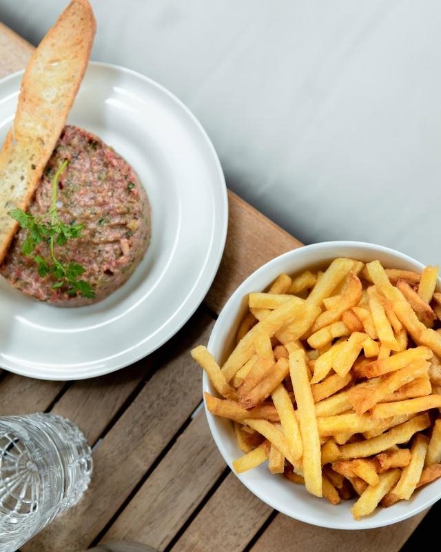 Tartare de bœuf charolais coupé au couteau, pain grillé et bol de frites maison.